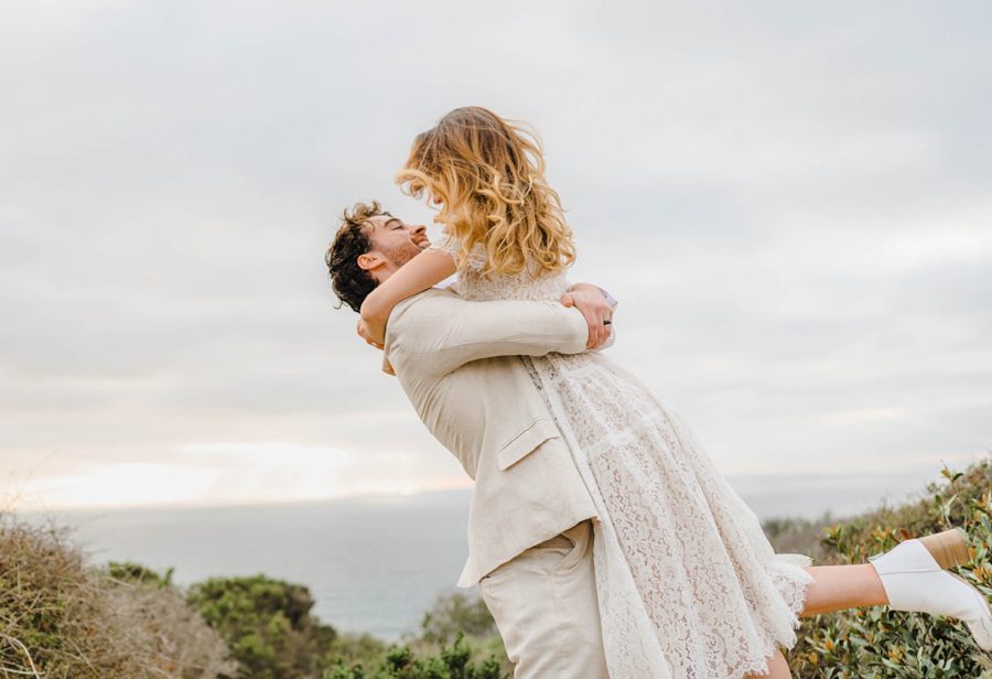 groom swinging bride beach landscape california