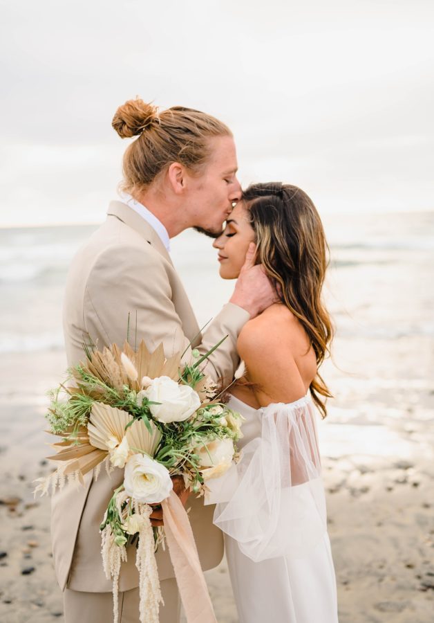 bride and groom kiss floral details beach elopement