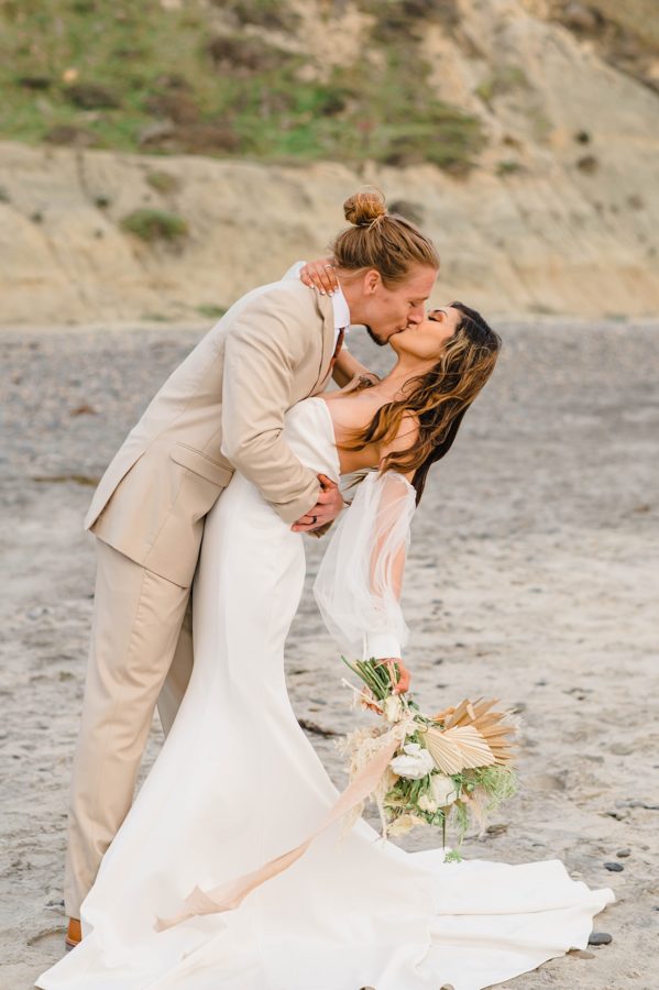 bride and groom kiss beach wedding florals
