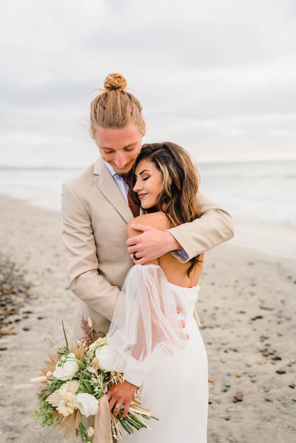 bride and groom hugging beach