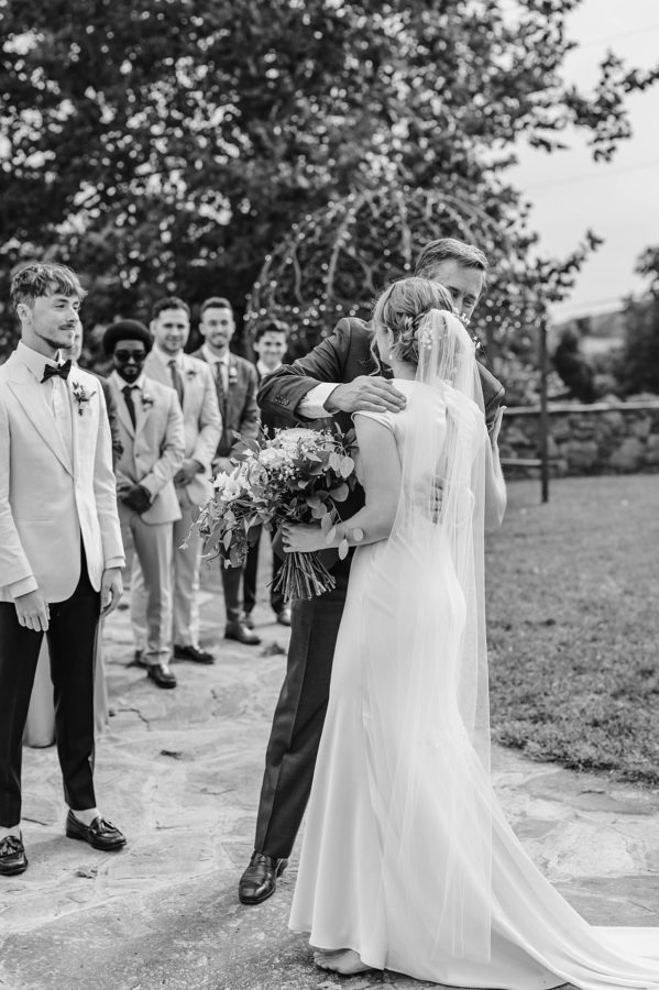 intimate bluemont vineyard wedding black and white bride hugging father of the bride