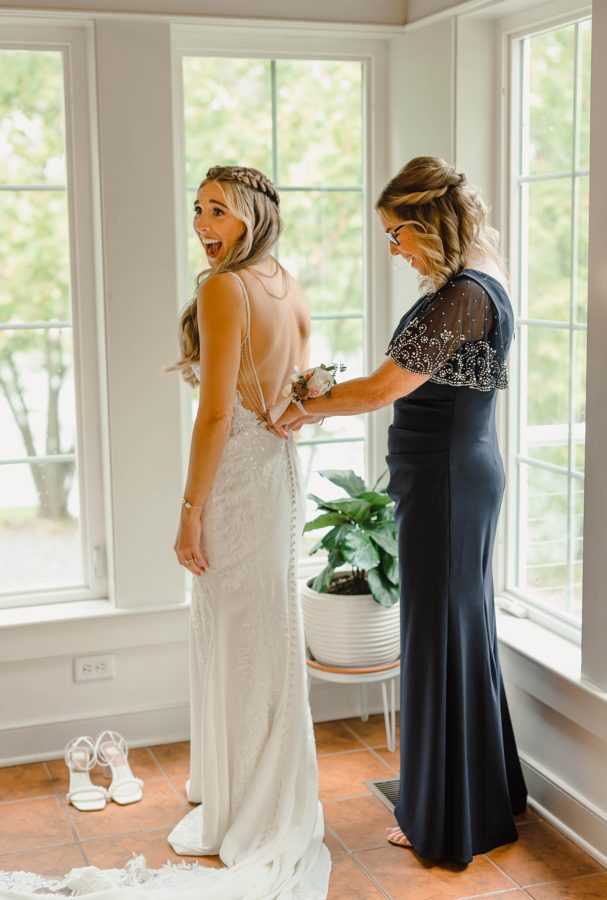 bride and mother of bride putting dress on moment