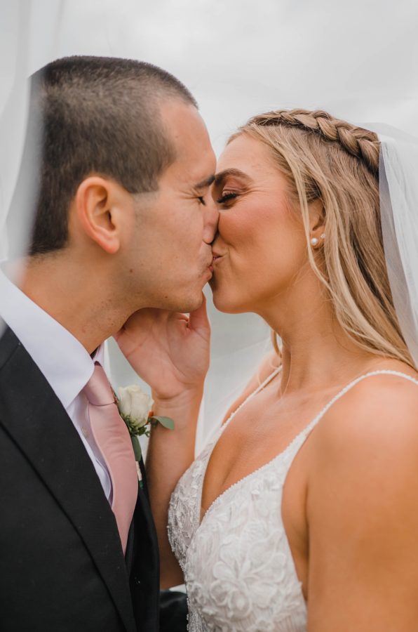 bride and groom kissing under veil portrait