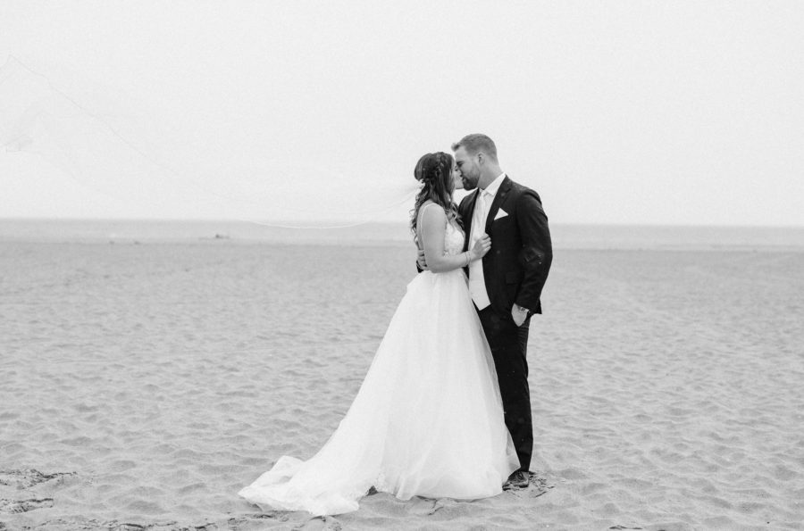 black and white beach bride and groom kissing wedding dress