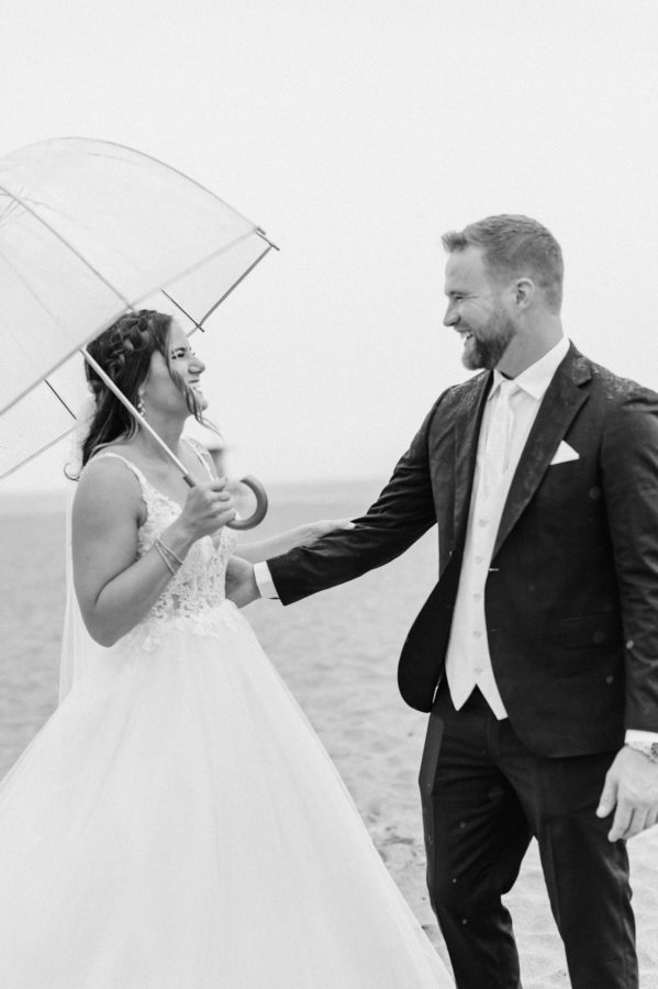black and white first-look wedding day bride and groom smiling umbrella
