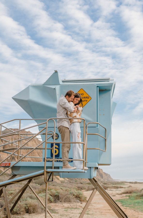 couple hugging lifeguard stand beach blue sky
