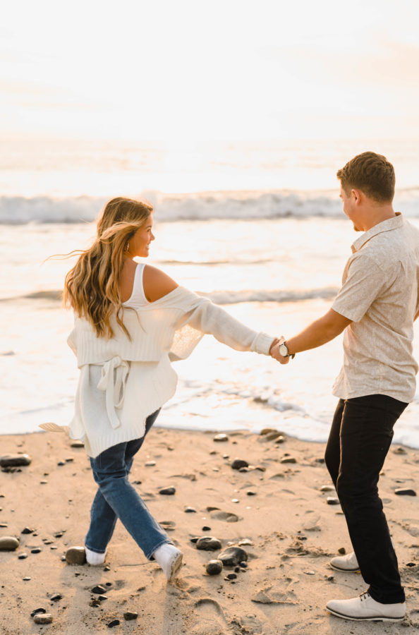 engaged couple holding hands smiling golden hour