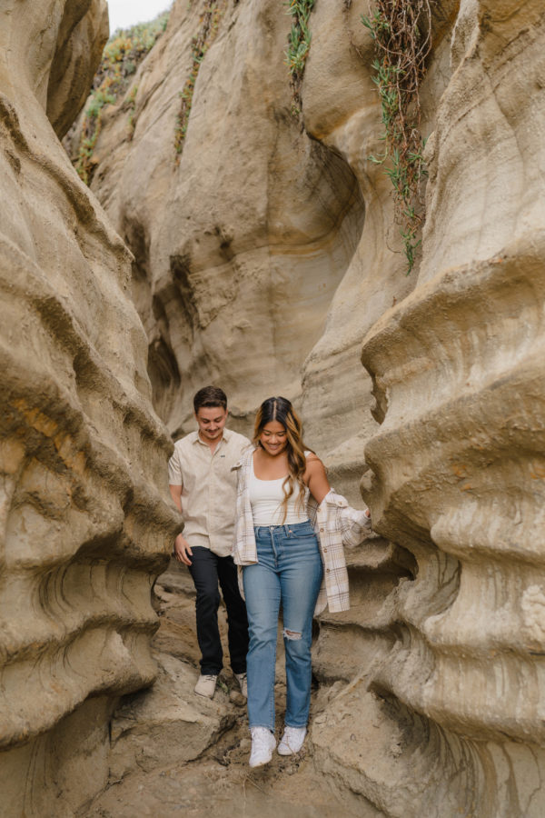 calafia beach engagement couple holding hands walking beach caves
