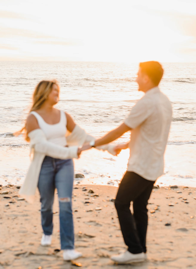 calafia beach engagement couple holding hands foreground blur