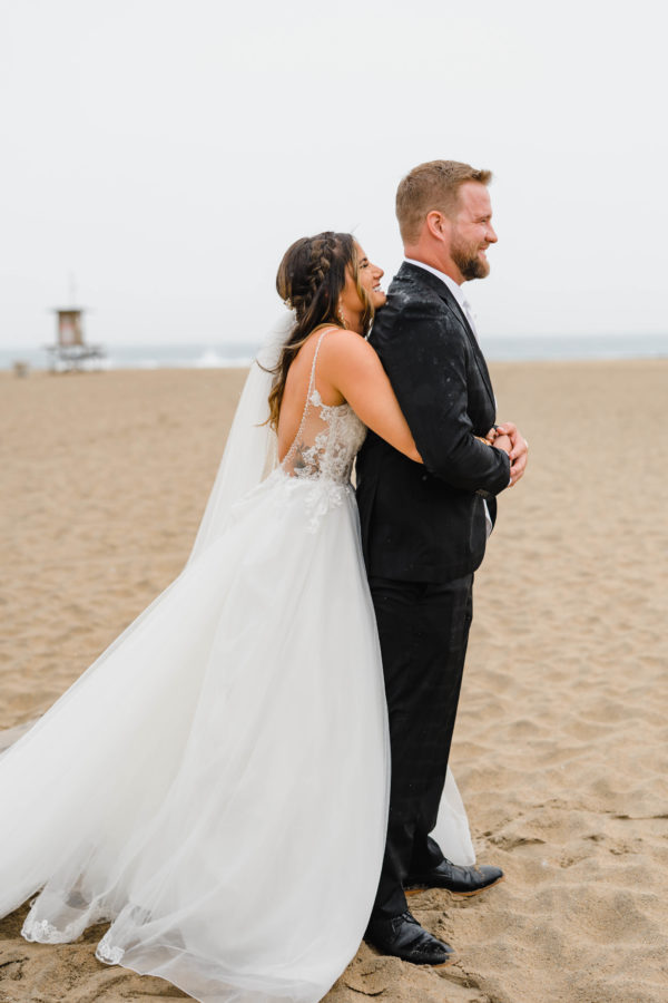 bride and groom hugging beach smiling