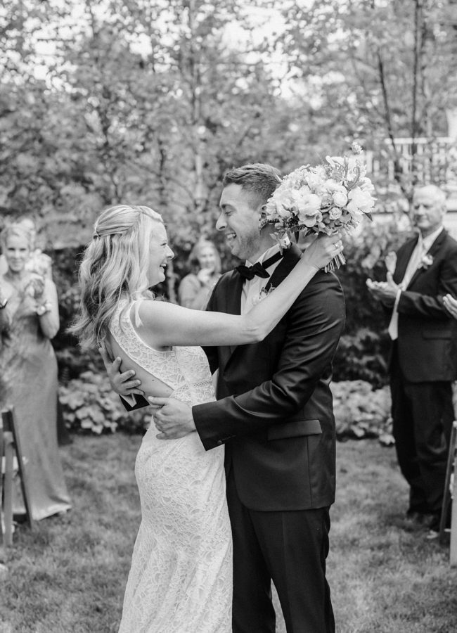 black and white portrait bride and groom hugging holding florals