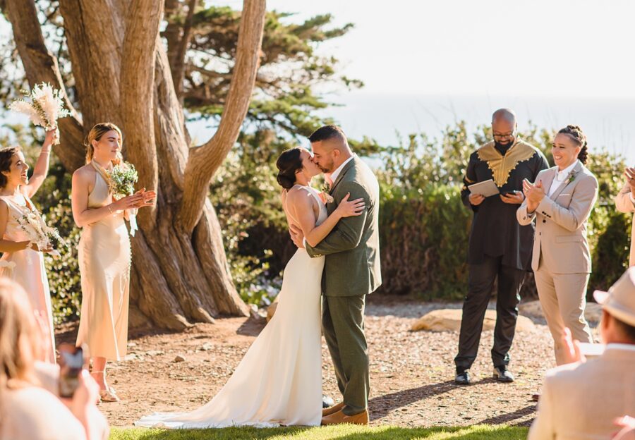 bride and groom kiss while other cheer
